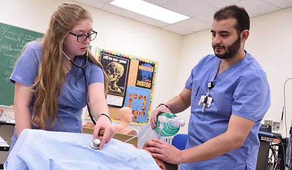 两个护理专业的学生一起在实验室里帮助病人.